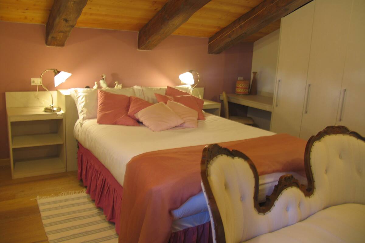 A bedroom with a bed, bedside tables, a wardrobe, and a chair.