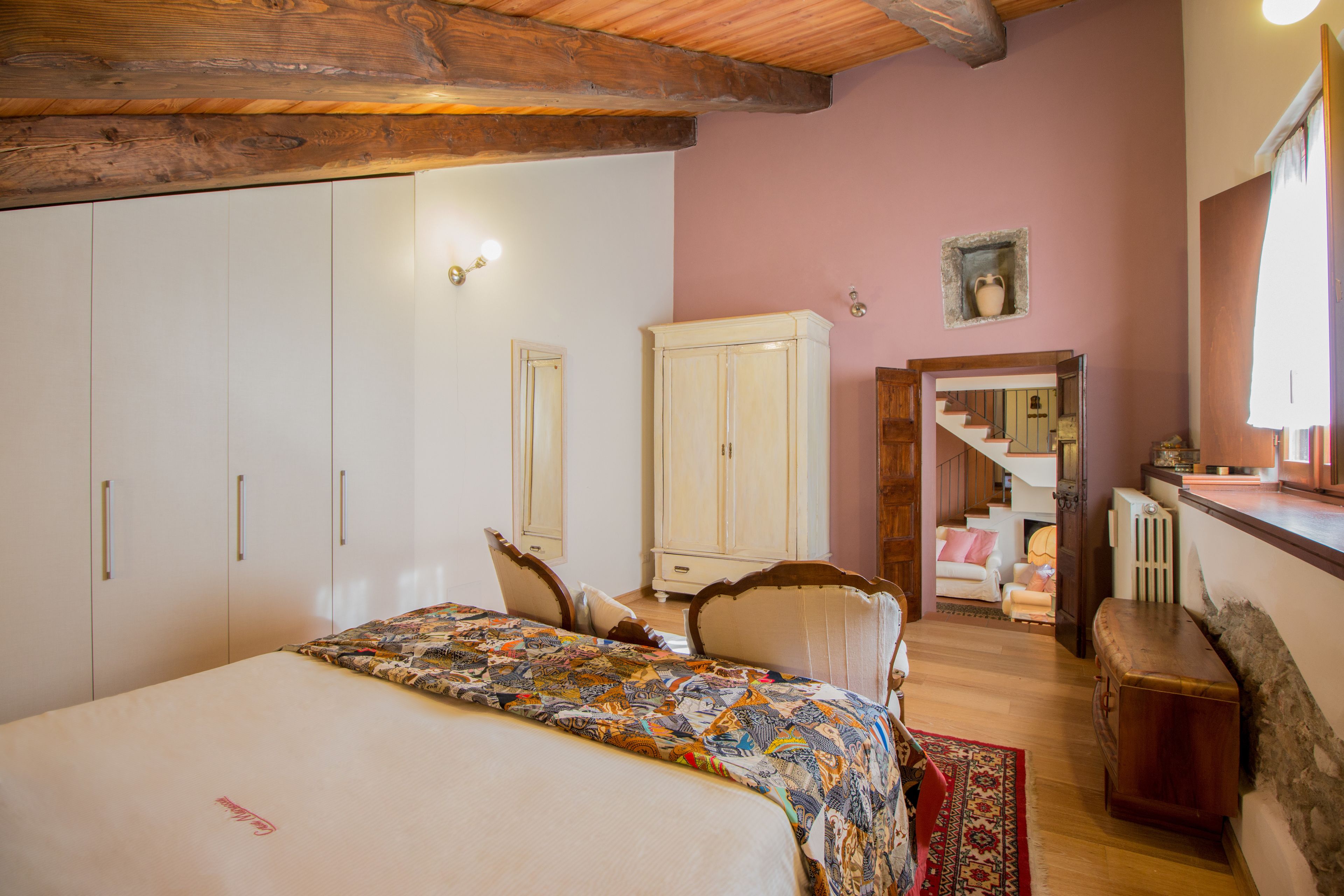 Ein Schlafzimmer mit einem großen Bett, einem Kleiderschrank, einer Kommode und einer Treppe zu einem anderen Raum.