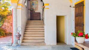 Un escalier menant à une pièce dotée d’une porte en bois, d’une plante en pot et d’un tableau accroché au mur.