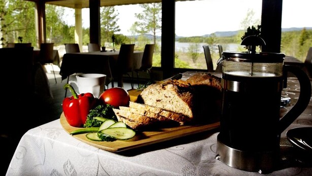 A table with sliced bread, a pitcher, and fresh vegetables. - Pan Garden Åmli Hotel (Amli)