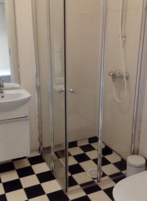A bathroom with a checkered floor, a sink, and a shower enclosure. - Pan Garden Åmli Hotel (Amli)