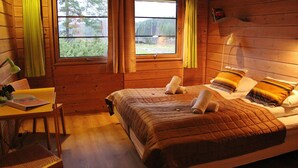 A wooden cabin room with a bed, a desk, and two windows. - Pan Garden Åmli Hotel (Amli)