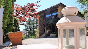 Un farol blanco, una maceta de terracota grande y un edificio con fachada de piedra y un balcón.