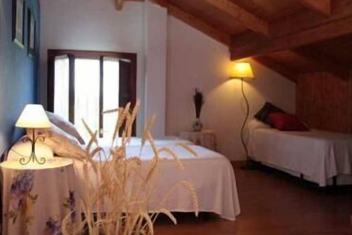 Une chambre à coucher avec un lit, une table de chevet, une lampe et une fenêtre.
