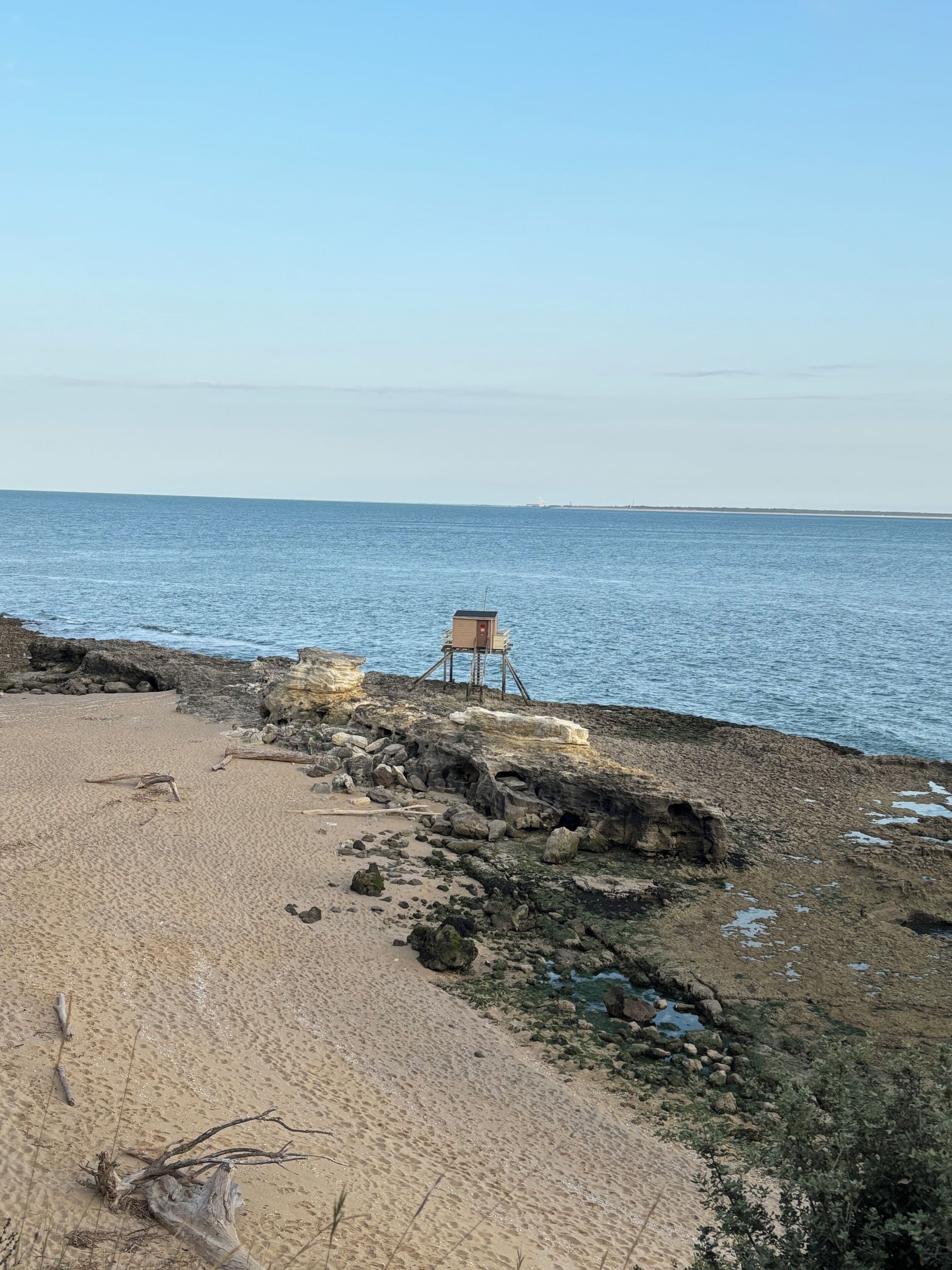 Une plage avec une chaise en bois et une petite construction, probablement un poste de surveillance pour les sauveteurs, sur une côte rocheuse.
