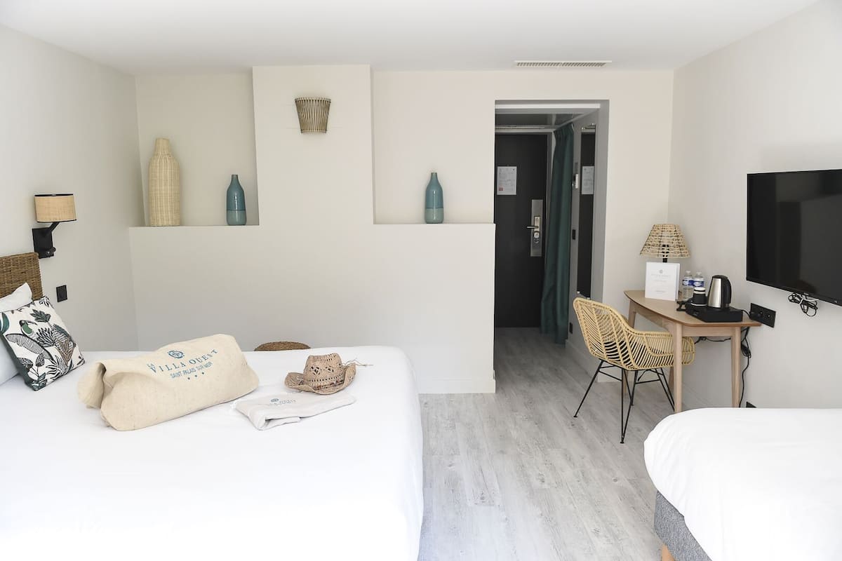 Une chambre d’hôtel équipée d’un lit, d’un bureau, d’une chaise, d’une télévision et d’une porte donnant sur une autre pièce.