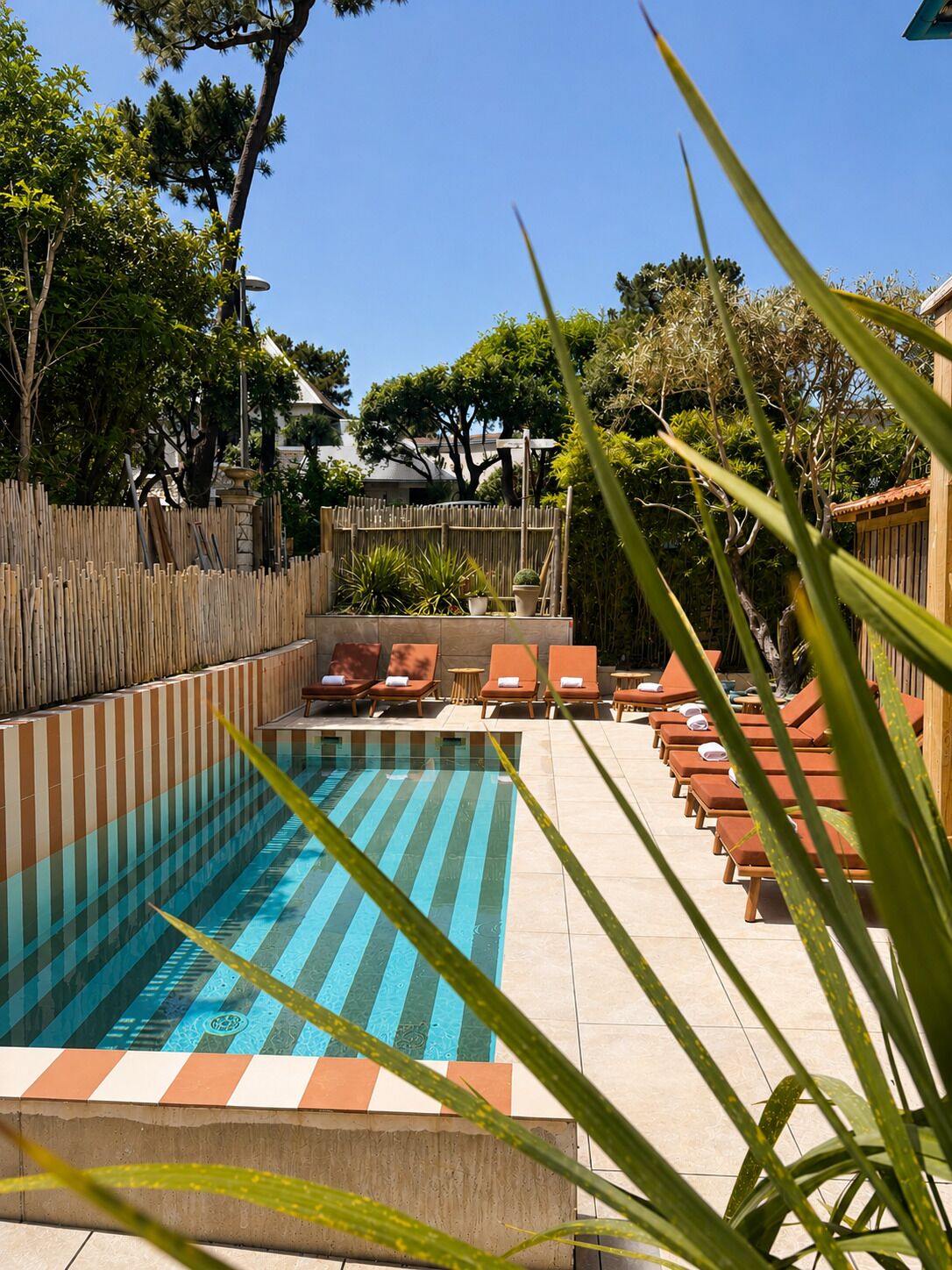 Piscina com espreguiçadeiras e cerca de madeira.