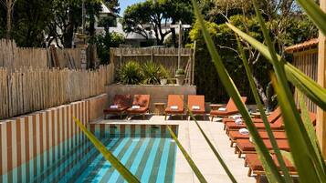 Piscina com espreguiçadeiras e cerca de madeira.