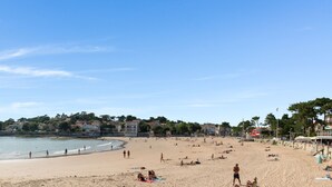 Une plage avec un mur de pierres et des bâtiments en arrière-plan.
