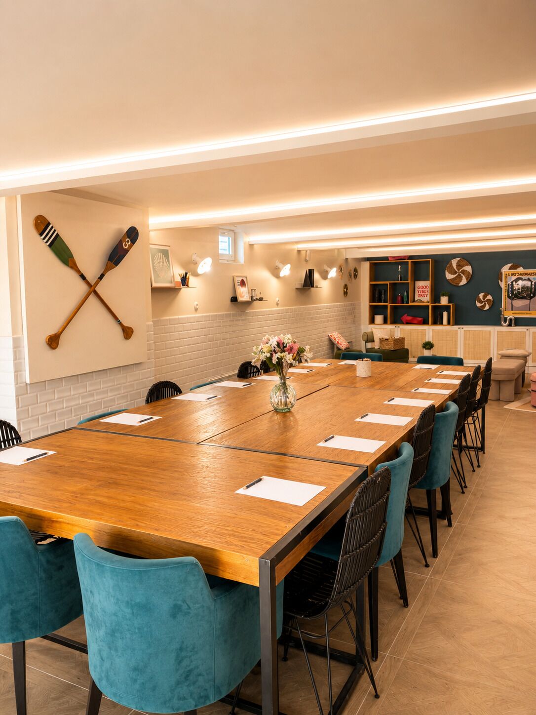 A conference room with a long wooden table, teal chairs, and a wall-mounted paddleboard.