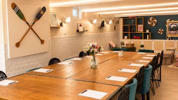 A conference room with a long wooden table, teal chairs, and a wall-mounted paddleboard.