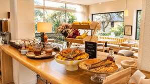 Un buffet de petit-déjeuner proposant une variété de plats, un menu écrit à la craie et une vue sur l’extérieur.
