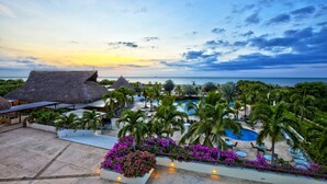 A resort with a pool, palm trees, and a sunset view. - Hotel Estelar Playa Manzanillo (Cartagena)