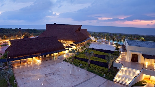 A resort with a thatched-roof building, a pool area, and a view of the ocean. - Hotel Estelar Playa Manzanillo (Cartagena)