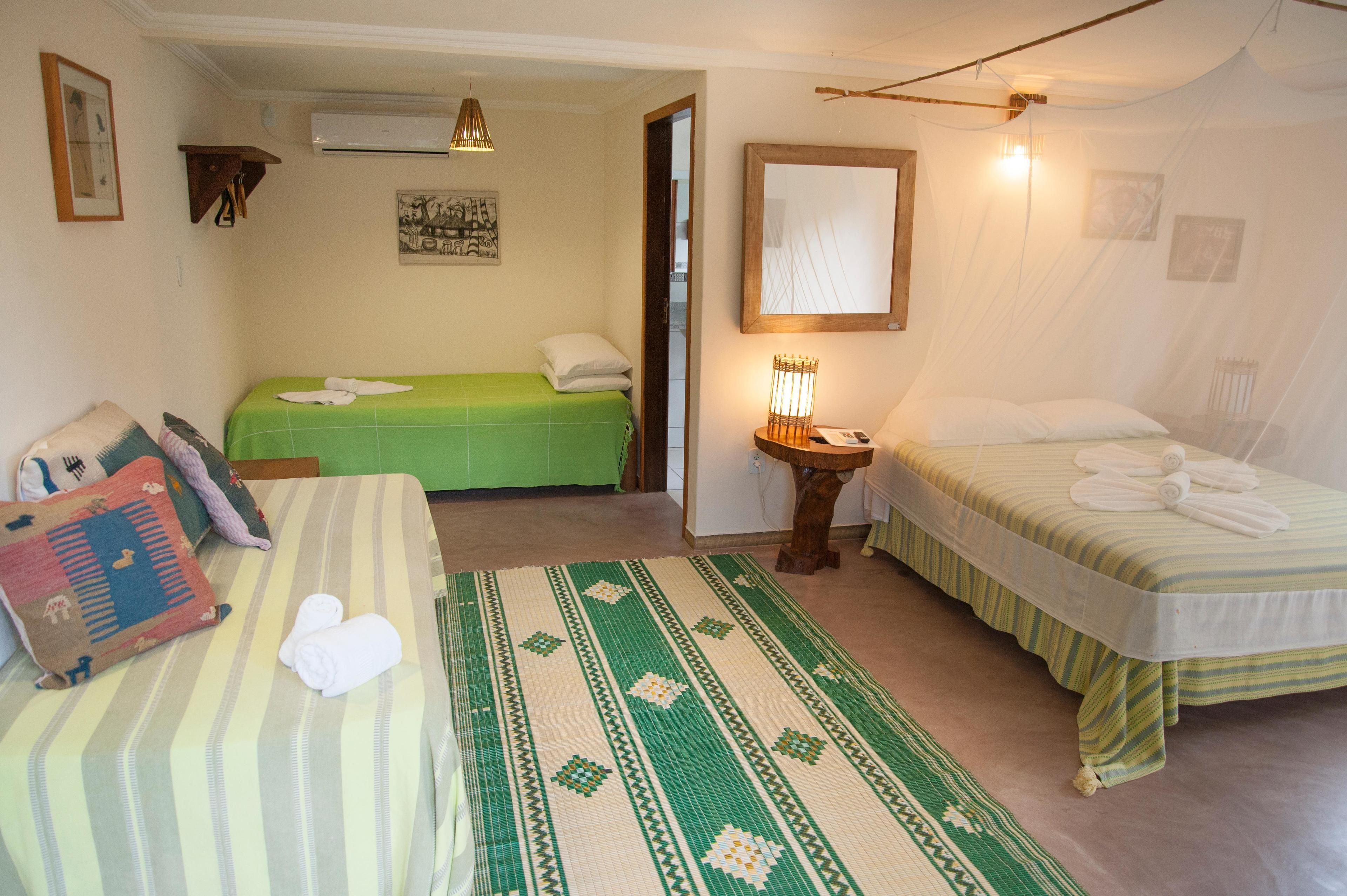 A room with two beds, a small table, and a wall-mounted mirror.