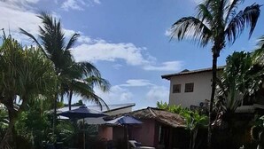 A swimming pool with tiled flooring, surrounded by palm trees and a small building. - Guest House Villa 2 Santos (Porto Seguro)
