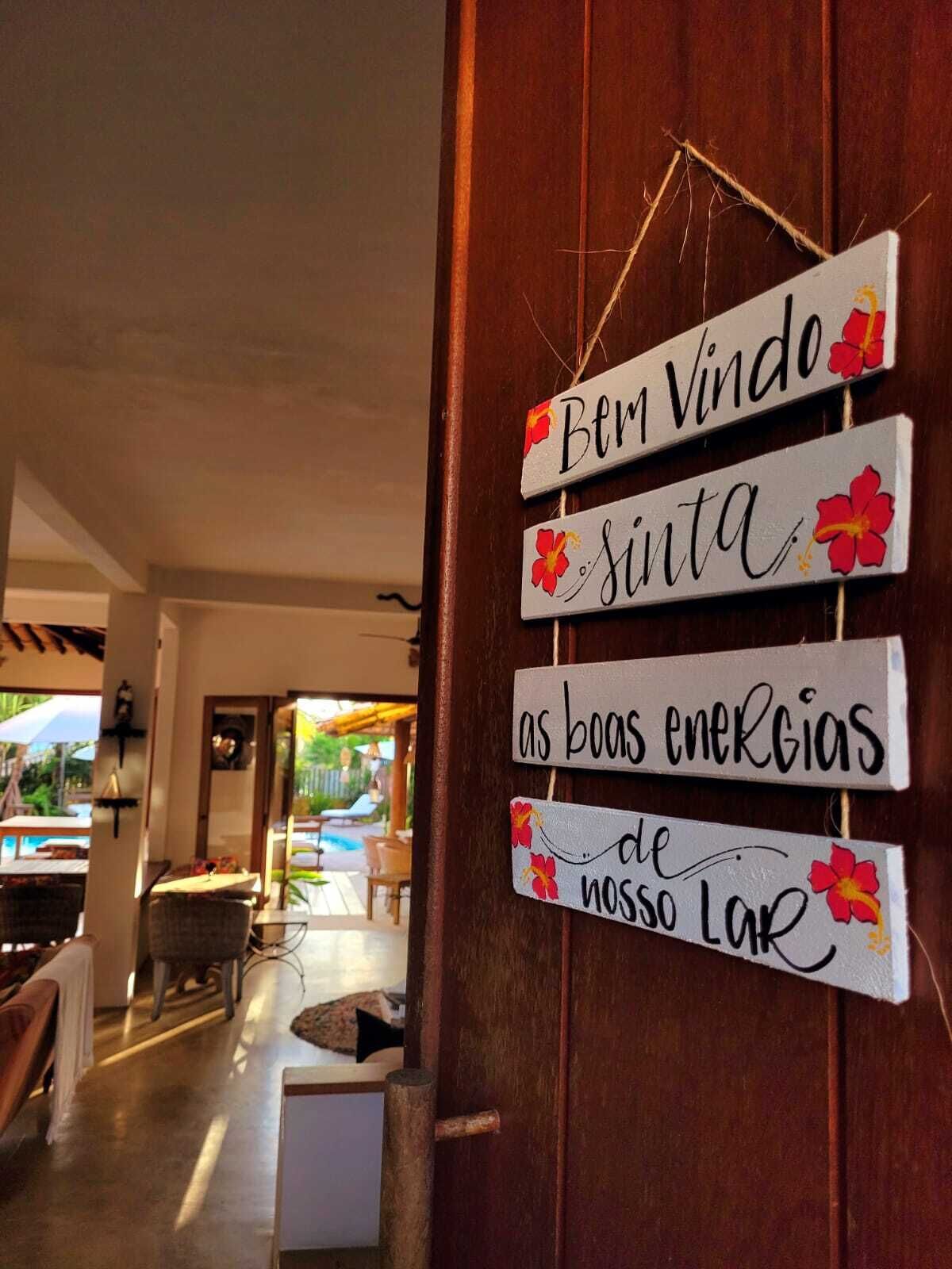A wooden door with a sign that reads "Bem Vindo" and "sinta as boas energias de nosso Lar".
