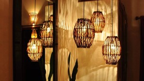 A dining area with a table, chairs, and hanging wicker lamps. - Guest House Villa 2 Santos (Porto Seguro)