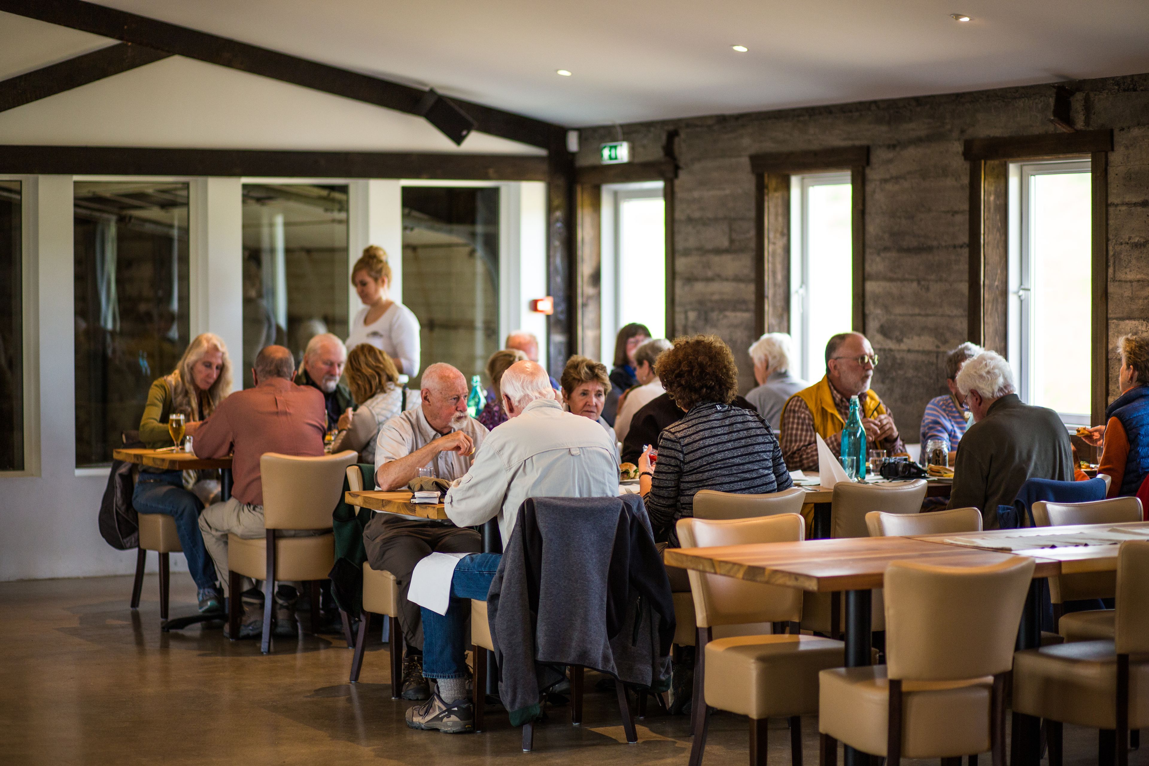 A spacious indoor dining area with multiple tables and chairs, large windows, and a modern architectural design.