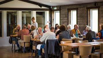 A spacious indoor dining area with multiple tables and chairs, large windows, and a modern architectural design.