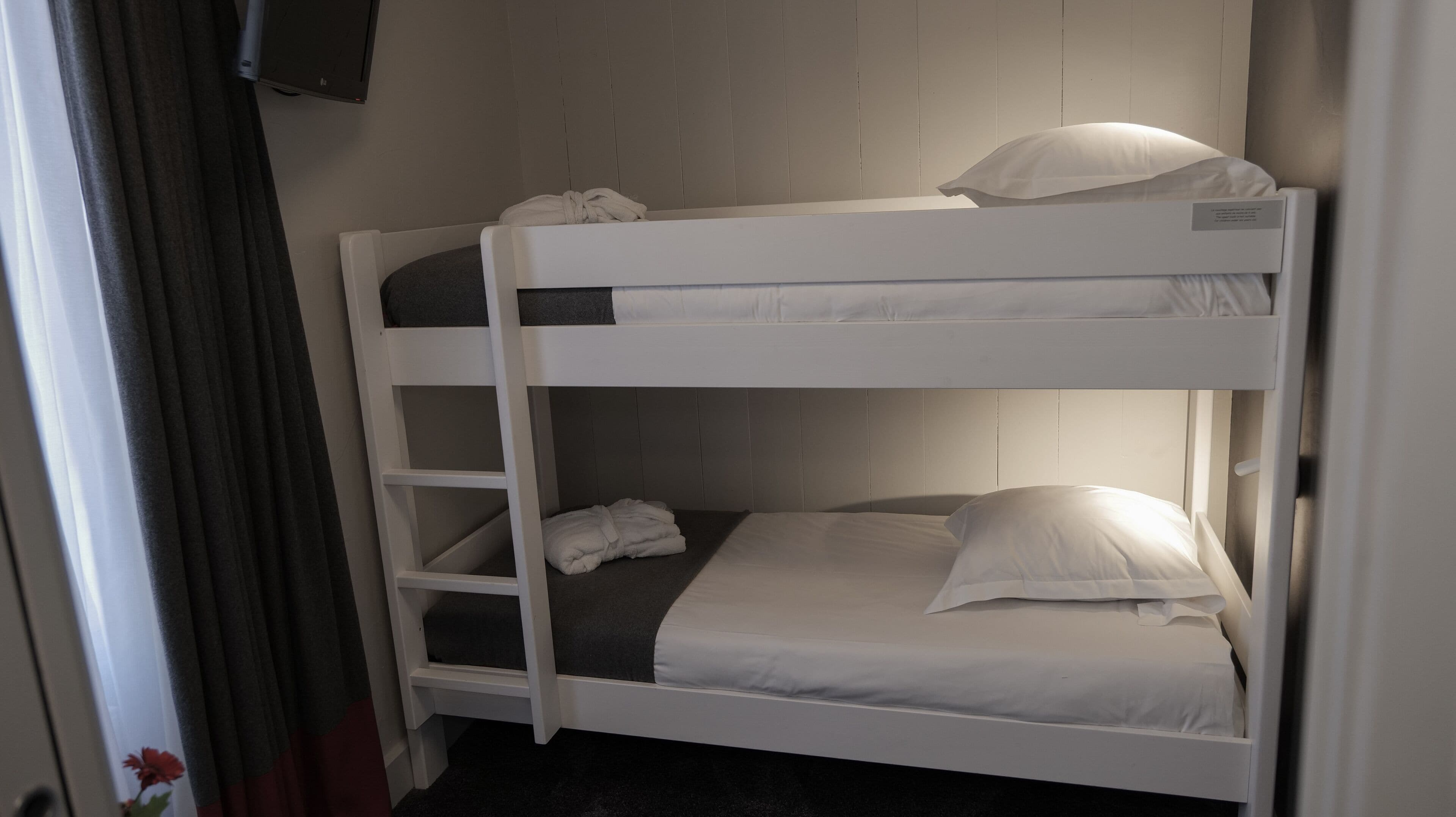 A bunk bed with white bedding and a ladder.