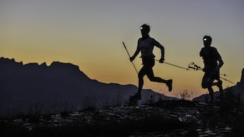 Two people running on a mountain trail with a sunset in the background.