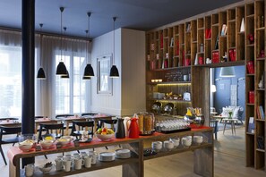 Enjoy a warm breakfast in our dining area, where a long table is set with fresh fruit, a pitcher, and a coffee pot.