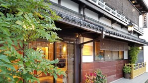 Een traditioneel Japans gebouw met een moderne entree, grote ramen en plantenbakken.