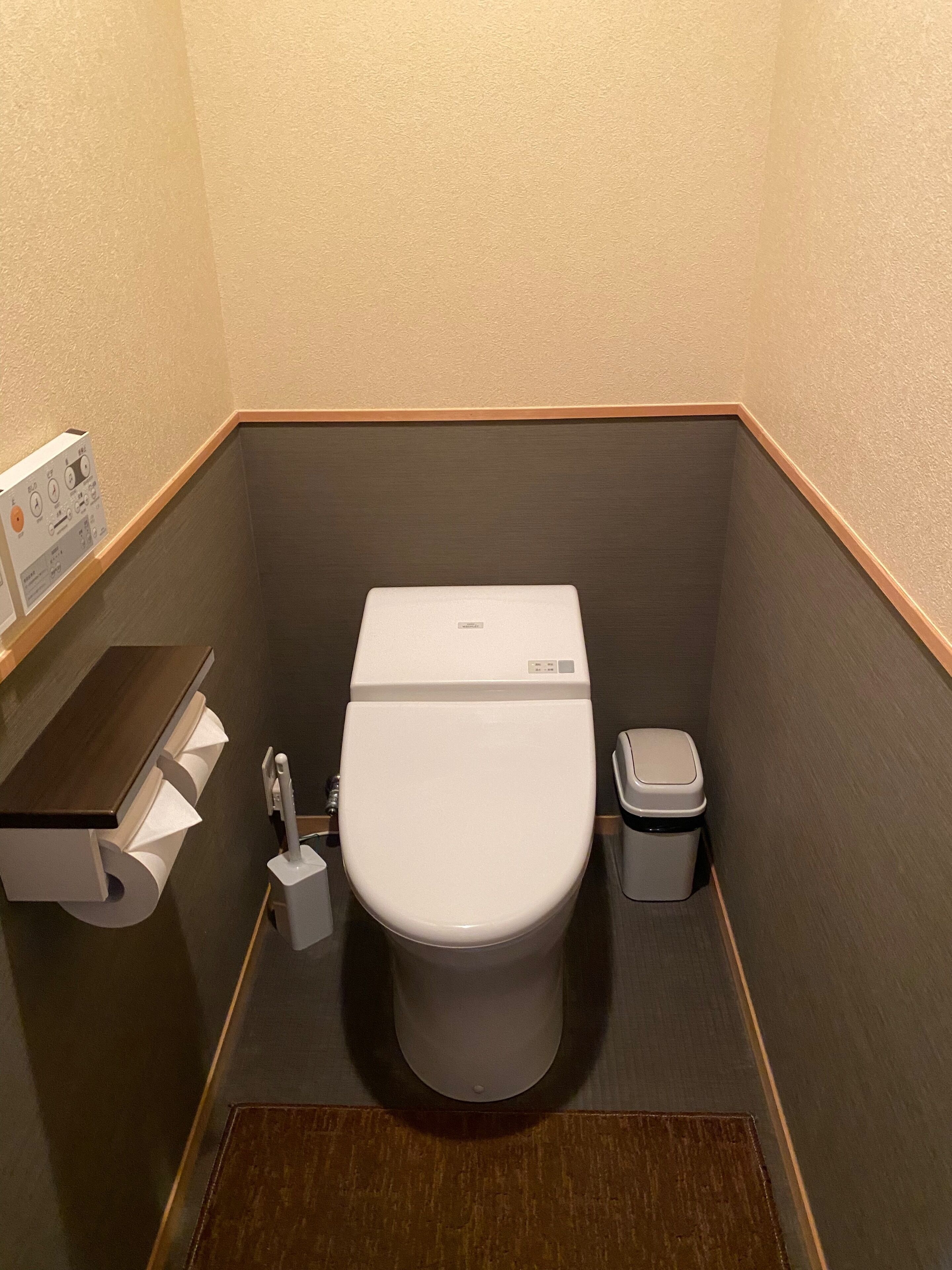 Ein kleines Badezimmer mit Toilette, Mülleimer und Toilettenpapierhalter.
