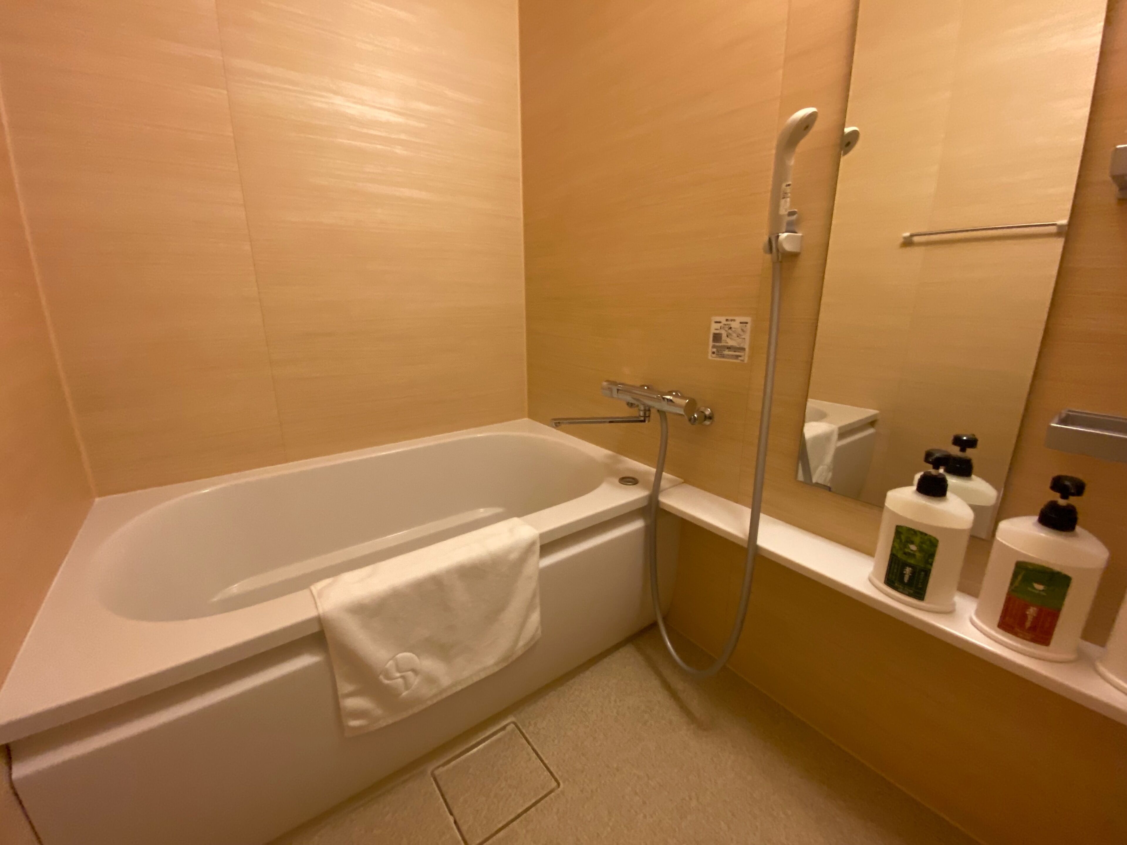 A bathroom with a bathtub, a shower, and a shelf with toiletries.