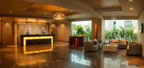 A modern lobby with a reception desk, seating area, and large windows. - Royal Orchid Central, Vadodara (Vadodara)