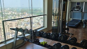 Un gimnasio con vistas a la ciudad, equipado con mancuernas, una cinta de correr y máquinas de pesas.