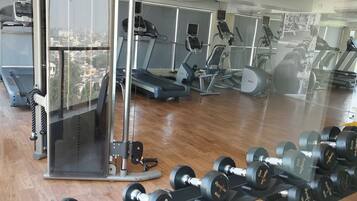 A gym with exercise equipment, a treadmill, and a mirror reflecting the room.
