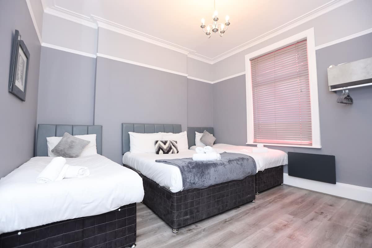 Une chambre d’hôtel avec deux lits, une grande fenêtre avec stores, un lustre et un climatiseur fixé au mur.