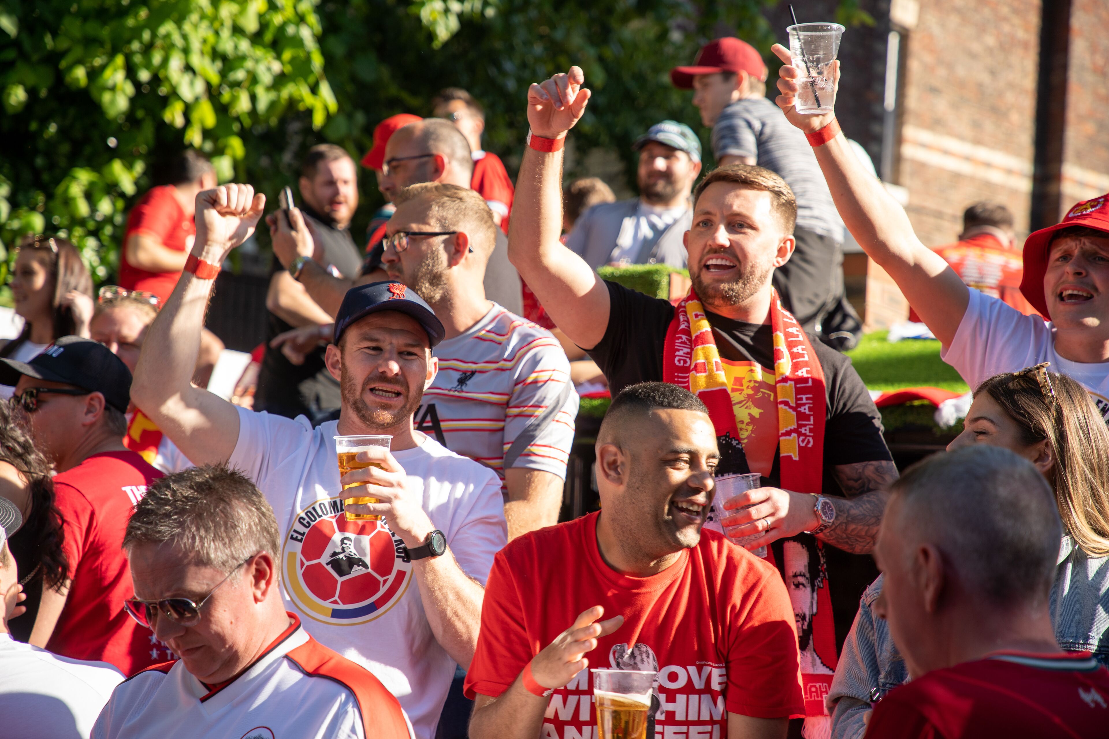 A group of people at an outdoor event, some wearing sports team apparel and scarves, suggesting a sports-related gathering.