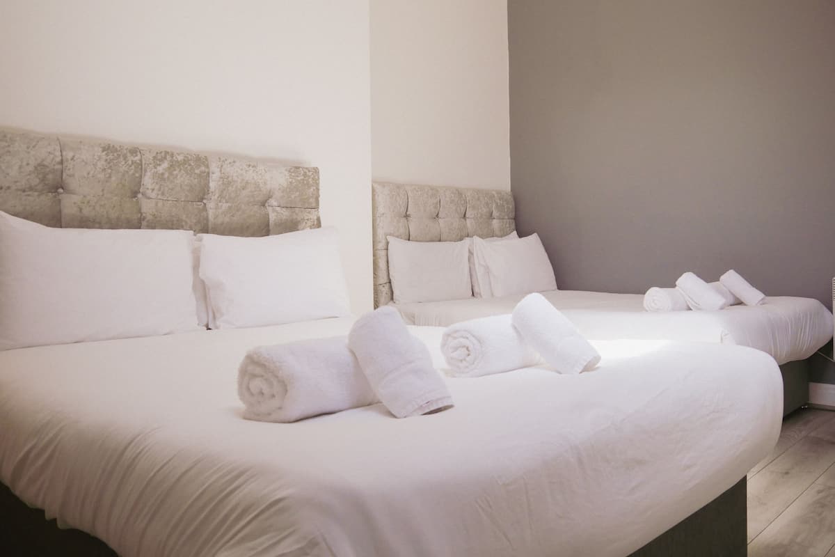 Une chambre d’hôtel avec deux lits, chacun doté d’une tête de lit, et des serviettes soigneusement pliées posées sur les lits.