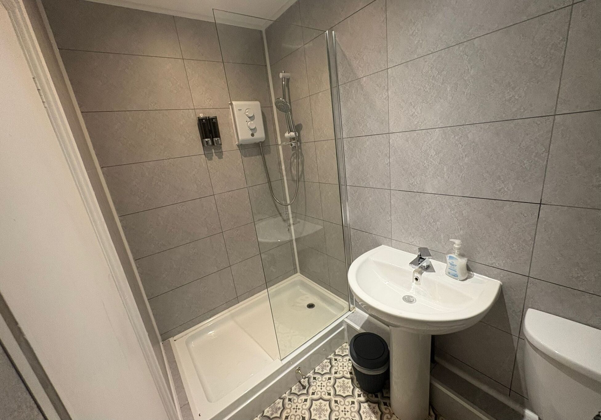 A bathroom with a glass-enclosed shower, a pedestal sink, and a toilet.