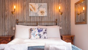A bed with white linens, a floral pillow, and two bedside tables with lamps. - The Blacksmiths Arms (Lewes)