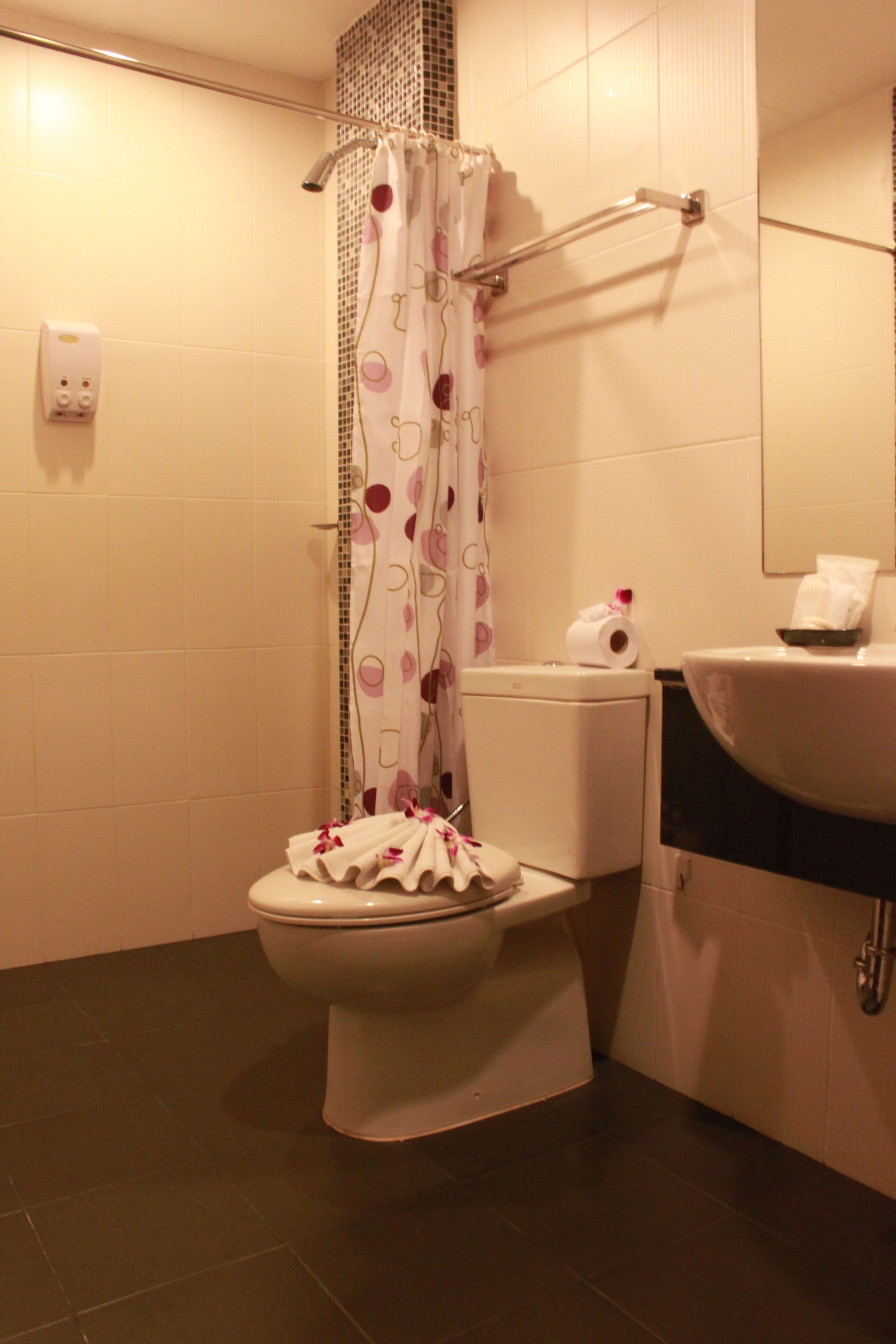 A bathroom with a toilet, a shower curtain, a towel rack, and a sink.
