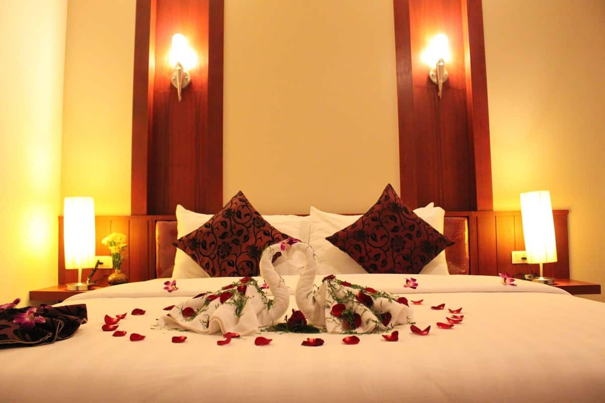 A hotel room with a large bed, two wall-mounted lamps, and decorative pillows.