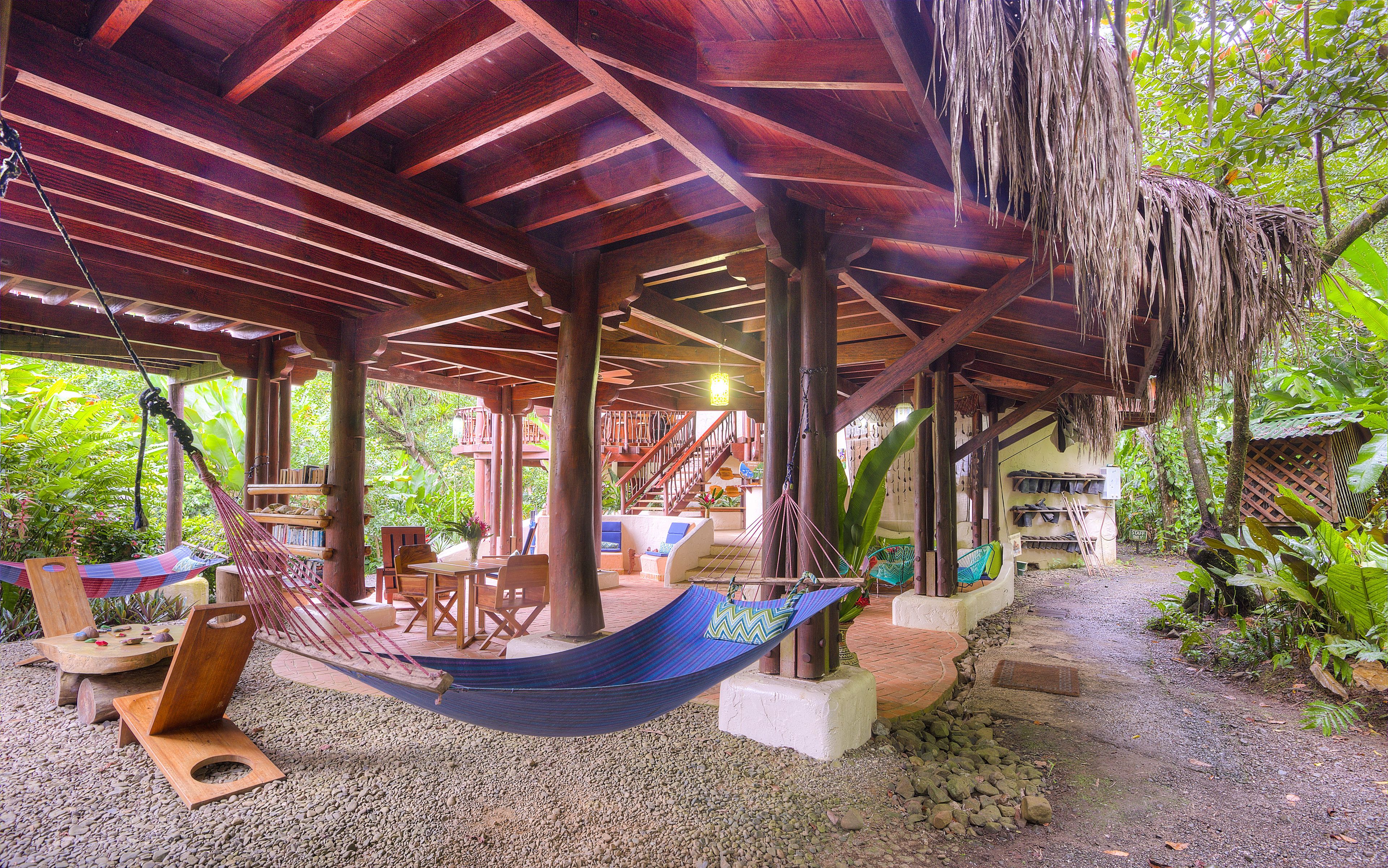 Un espacio al aire libre cubierto con una hamaca, asientos y una escalera que lleva a un nivel superior.