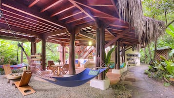 Un espacio al aire libre cubierto con una hamaca, asientos y una escalera que lleva a un nivel superior.