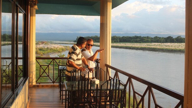 A balcony with a view of a river and distant mountains. - Jungle Wildlife Camp (Sauraha)