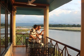 A balcony with a view of a river and distant mountains.