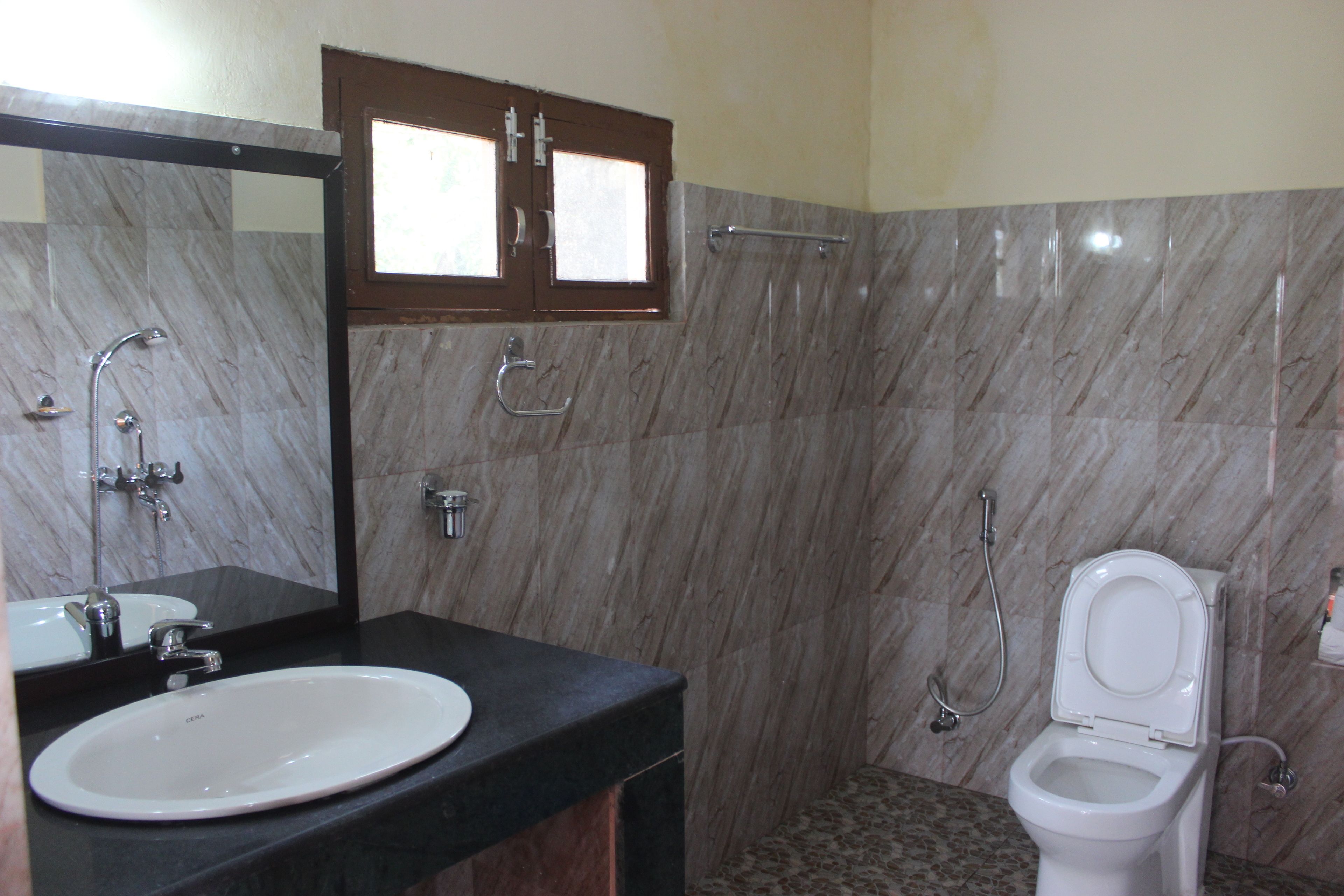 A bathroom with a marble wall, a sink, a toilet, and a shower.