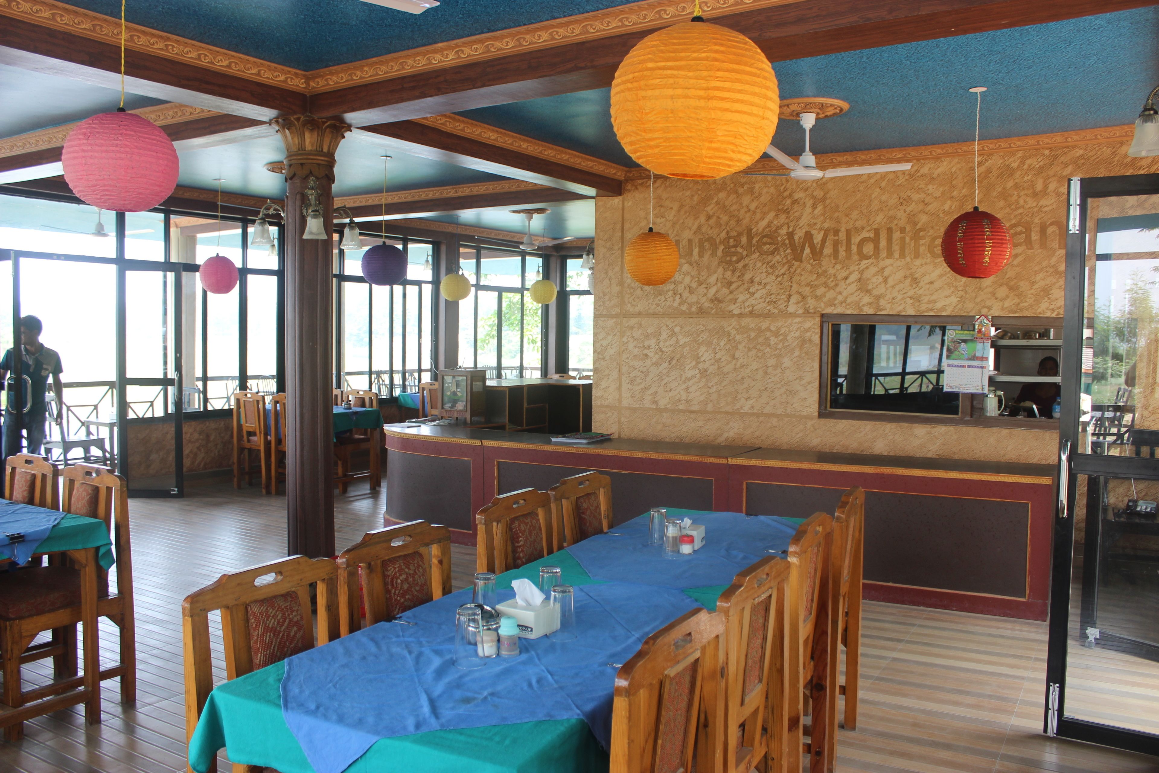 A restaurant with wooden tables and chairs, a bar area, and hanging paper lanterns.