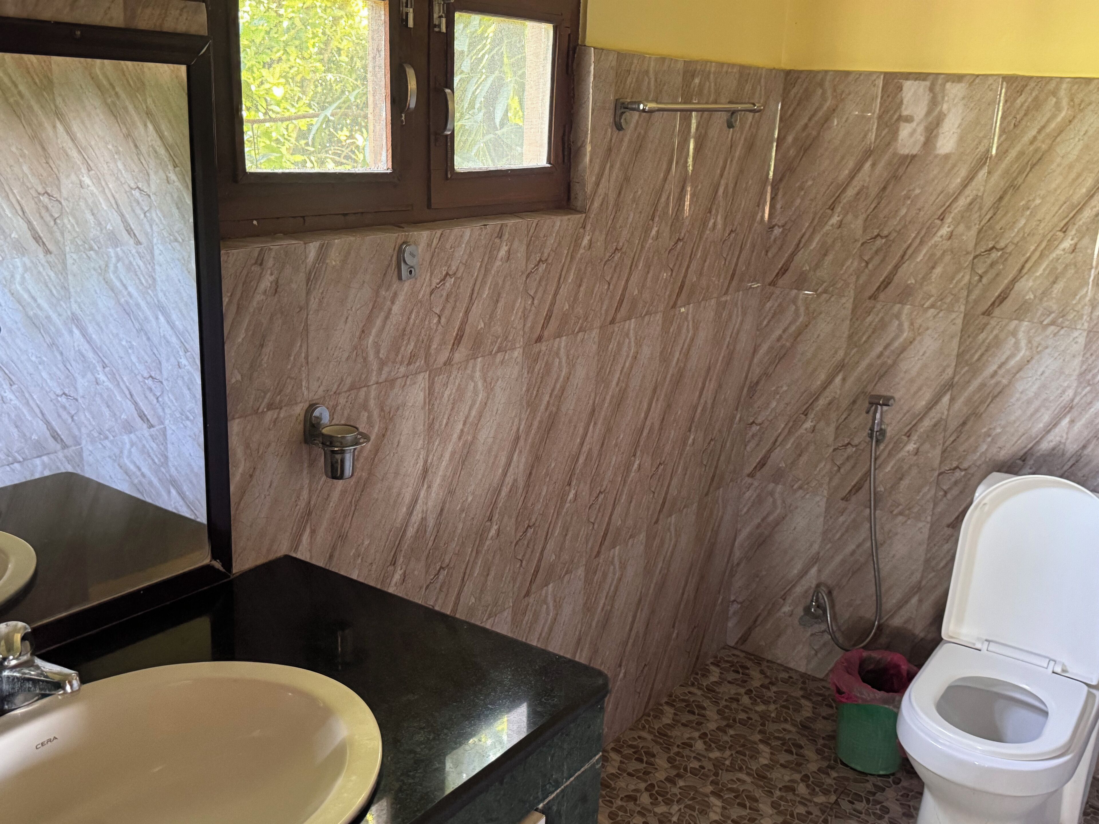 Une salle de bain avec un mur en marbre, un lavabo, des toilettes et une douche.