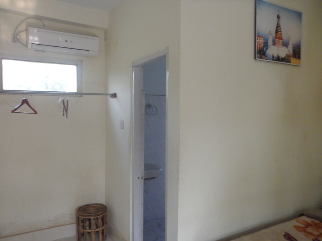 Una habitación con ventana, aire acondicionado, una puerta y una pequeña cesta de mimbre.