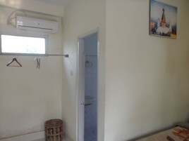 Una habitación con ventana, aire acondicionado, una puerta y una pequeña cesta de mimbre.