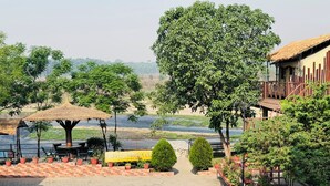 A riverside view with a thatched umbrella, seating, and potted plants. - Jungle Wildlife Camp (Sauraha)